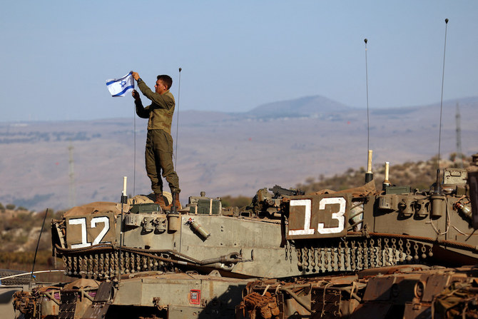 軍事訓練の最中、戦車にイスラエル国旗を立てる兵士。イスラエル北部のレバノンとの国境付近。（ロイター）