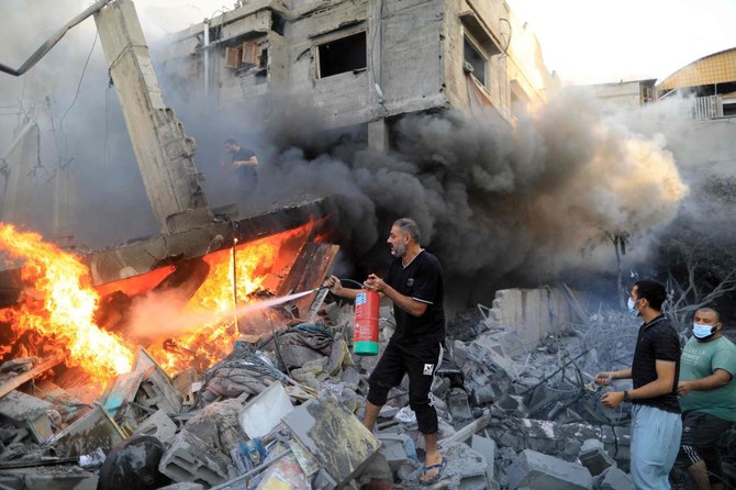 2023年10月14日、ガザ地区南部のカン・ユニスで、イスラエル軍の空爆後の火災を消火器で消すパレスチナ人男性。(AFP)
