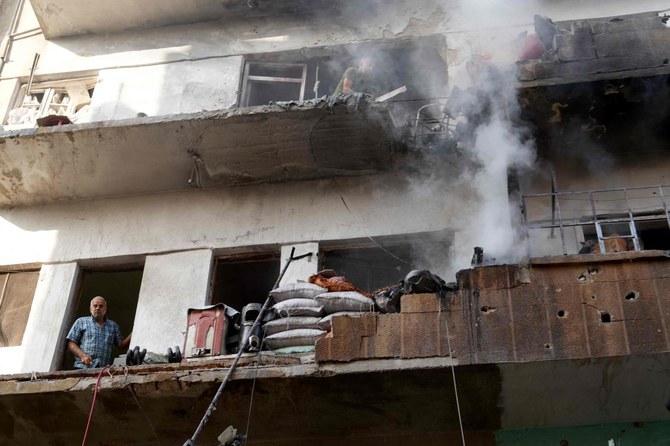 シリアの親政府軍の砲撃が直撃し、損傷した建物のバルコニーにシリア人男性らが立っている。2023年10月7日、反政府勢力が支配する北西部のイドリブで撮影。(AFP通信)