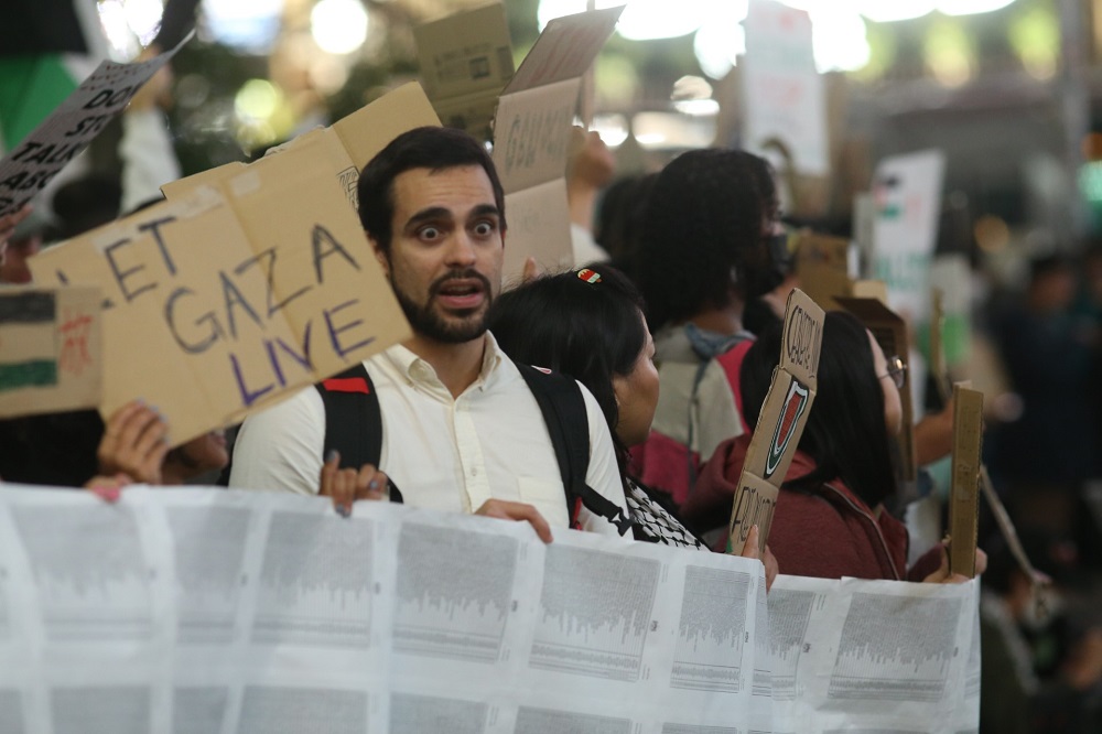 デモ参加者たちは、ガザ保健当局が発表した犠牲者たちの名前を記した長いバナーを掲げて行進した。(ANJ)