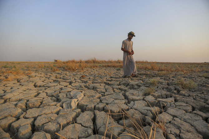 イラクのディカル州にある湿地帯で、乾燥した地面の上を歩く漁師(AP通信)