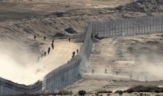 有刺鉄線フェンスを越えるイスラエル軍。2023年11月13日、イスラエル南部のガザ地区との境界沿いの場所から撮影された写真。（AFP/ファイル）