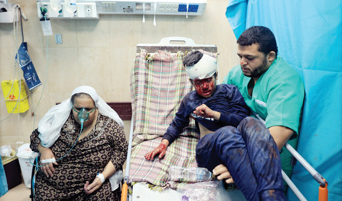 16日、イスラエル軍によるガザ地区中央部のデリ・エル・バラへの爆撃後、負傷した少年を医師がアル・アクサ病院に運び込んだところ。（AFP）