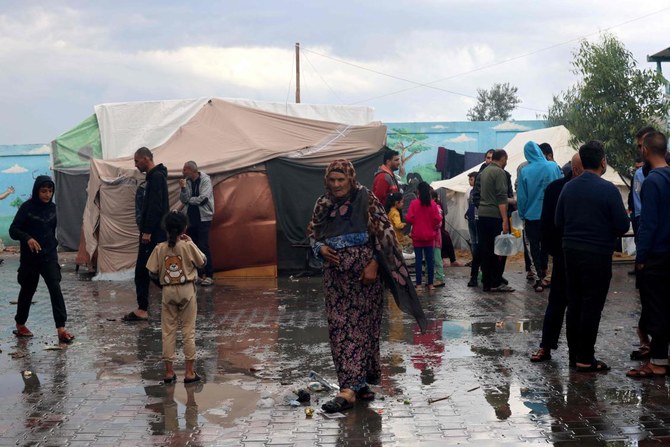 パレスチナ難民のための国連機関(UNRWA)が運営する学校で暮らす国内避難民のパレスチナ人女性が、夜通しの暴風雨の後、湿った中庭をスリッパで歩いている。2023年11月15日、ガザ地区南部のラファにて。(AFP)