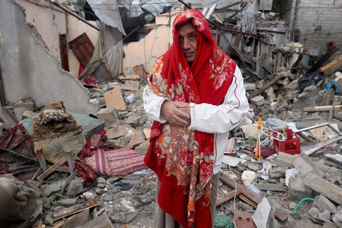 2023年11月15日、ガザ地区南部のラファ難民キャンプへのイスラエルの爆撃のあと、住宅の瓦礫の中に立つ、毛布をかぶったパレスチナ人男性。(AFP)