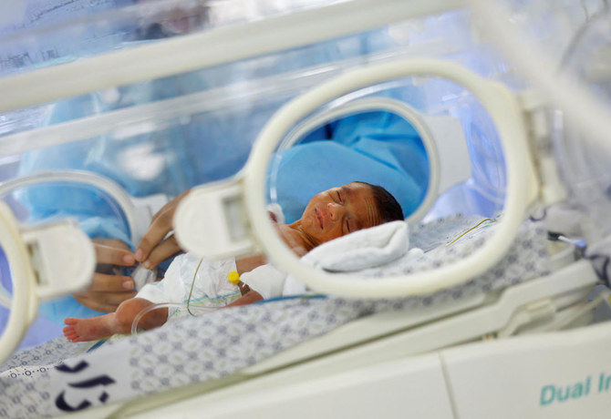 2023年11月19日、イスラエルと武装組織ハマスの戦闘が続く中、シファ病院からガザ地区南部の町ラファのエミレーツ病院に避難した未熟児の世話をするパレスチナ人医師。（AFP）