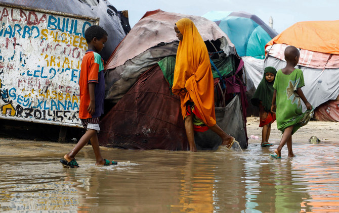 モガディシュ郊外での大雨の後、国内避難民のためのAl-Hidayaキャンプの仮設の避難所で洪水で発生した水の中を歩く住民たち（ロイター)
