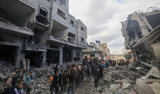 2023年11月20日、イスラエル軍の攻撃を受けたガザ地区南部のラファで、破壊された建物の瓦礫の中を歩くパレスチナ人。（AFP）