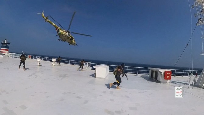 2023年11月20日公開された写真。フーシ派の軍用ヘリコプターが貨物船「ギャラクシー・リーダー」の上空でホバリングする中、フーシ派の戦闘員が船の甲板を歩いている。（フーシ派/ロイター）