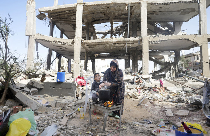 ガザ地区ハーン・ユーニス東部のクザア村で、破壊された家を訪れるパレスチナ人たち。戦闘休止により、住民たちは束の間の休息を得ている。（AP）