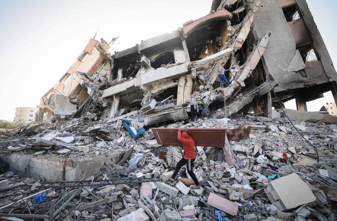 イスラエルとハマスの休戦協定が3日目を迎えた2023年11月26日、ガザ市南郊のアル・ザハラで、破壊された建物のがれきの中を歩くパレスチナ人。(AFP＝時事）