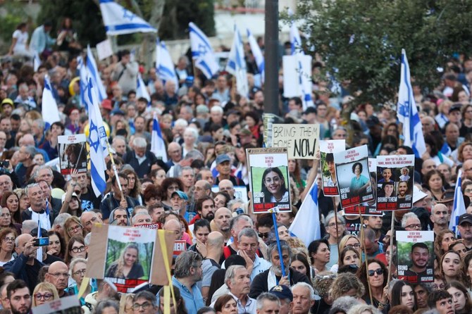 2023年11月18日、エルサレムの首相官邸前で人質解放を求めて抗議するイスラエルの人々。10月7日のイスラエル南部での武装組織ハマスによる奇襲攻撃以降、ガザ地区で拘束されている人質の写真、イスラエル国旗、プラカードを掲げている。（AFP）