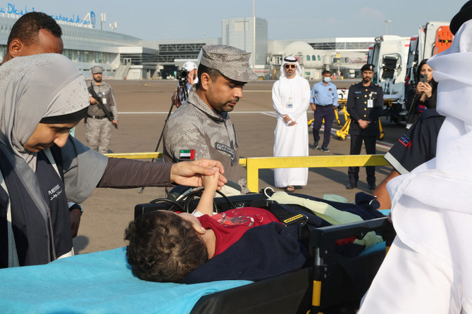 UAEが組織する人道ミッションの一環としてガザ地区から避難しアブダビに到着した、負傷したパレスチナ人の子どもたちを航空機から降ろすボランティアたち。（AFP）