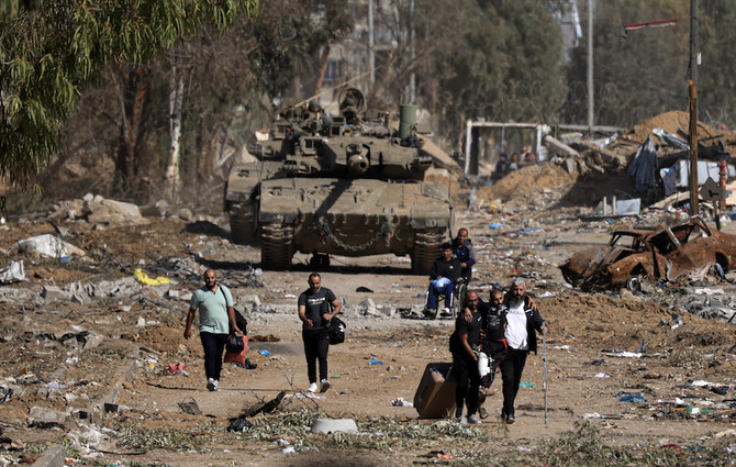 11月24日に始まった一時停戦を利用し、イスラエル軍の巨大な戦車を通り越して、ガザ北部から退避するパレスチナの民間人たち。（AFP）
