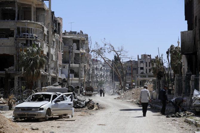 2018年4月16日、ダマスカス近郊で、化学兵器の使用が疑われる攻撃で破壊されたドゥーマの町の中を歩くシリア人。（AP/ファイル）