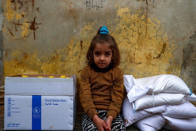 援助打ち切りを前に、アティマのキャンプで国連の支援機関、世界食糧計画（WFP）から送られた支援物資の包みの間に座るシリア難民の少女。（AFP）