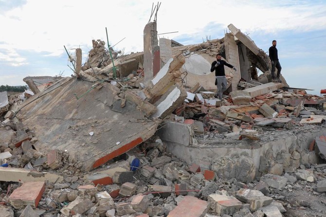 イスラエル軍による夜通しの空爆で破壊された家屋の瓦礫から、荷物を回収しようとする人々。2023年12月8日、国境に近いレバノン南部のマジュダル・ズーン村にて撮影。（AFP通信）