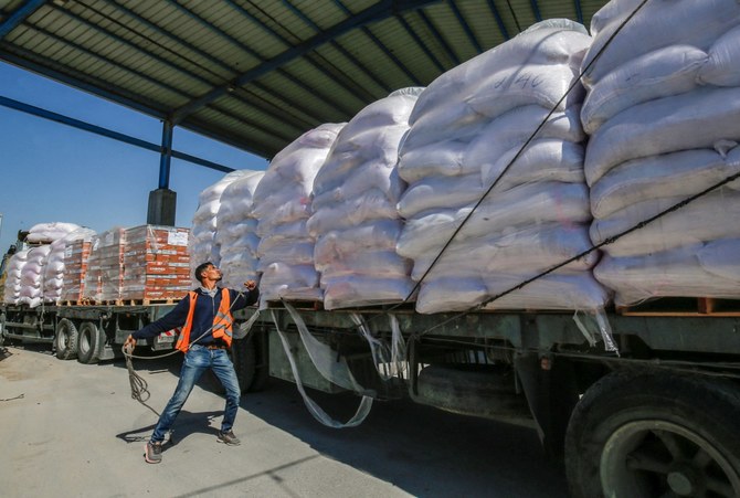 ガザ地区南部の都市ラファのケレム・シャローム検問所から到着した国連パレスチナ難民救済事業機関（UNRWA）の支援物資を積んだトラックを確認するパレスチナ人労働者。2019年の資料写真。