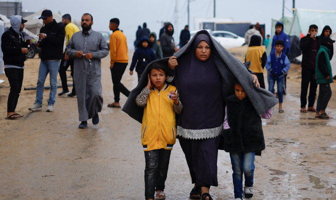 2023年12月13日、ガザ地区南部のラファ。イスラエルとハマスの戦闘が続く中、イスラエル軍の攻撃で家を追われたパレスチナ人が、大雨後のテントキャンプを歩く様子。（ロイター通信）