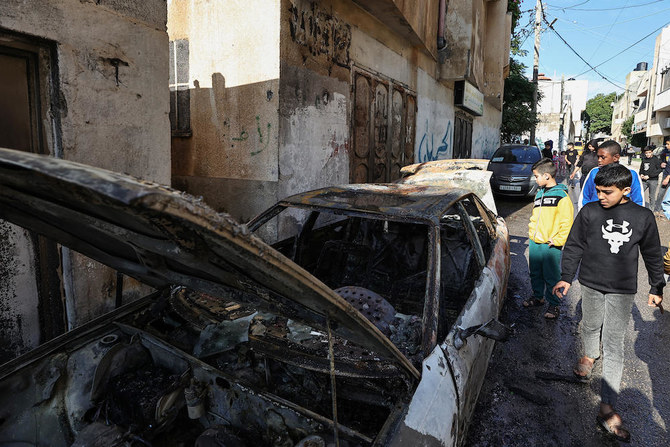 占領下にあるヨルダン川西岸地区のアル・ファラ村で、イスラエル軍による先の襲撃で焼けた落ちた車を確認するパレスチナ人。2023年12月8日撮影。(AFP）