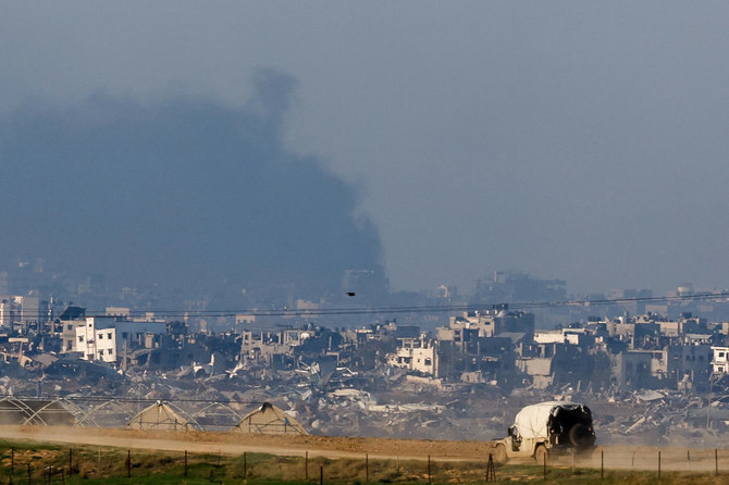 2023年12月19日、イスラエルとハマスの紛争が続く中、ガザ地区で破損した建物の近くを走るイスラエル軍の車両。(ロイター）