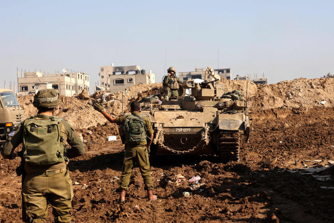 2023年12月19日、ガザ地区北部での軍事作戦中、戦車の横に立つイスラエル兵。(AFP＝時事）