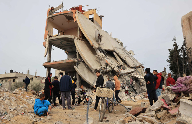 イスラエルと過激派組織ハマスの戦闘が続く中、2023年12月21日にガザ地区南部のハーン・ユーニスでイスラエルによる砲撃を受けて生じた瓦礫を確認するパレスチナ人たち。（AFP）