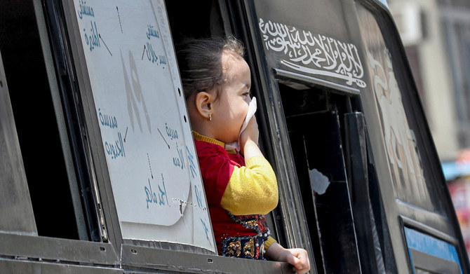 口をティッシュで守った少女がバスの窓越しに眺める（エジプト、カイロ、2020年4月12日）