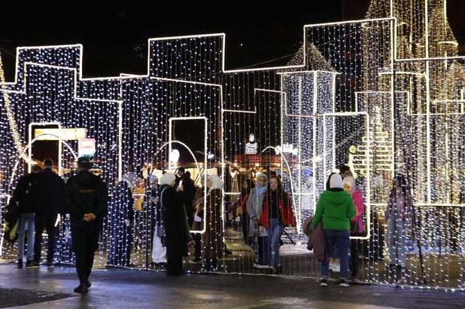 首都ダマスカスの市場でクリスマスの飾り付けの前を通り過ぎるシリア人。(AFP)