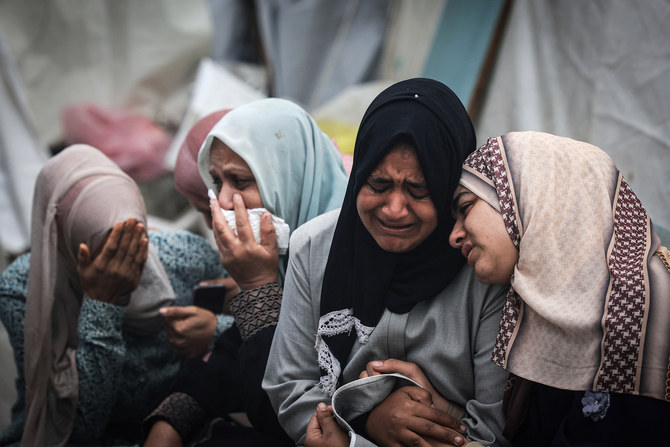 ガザでの集団葬で、イスラエルによるアル・マガジ難民キャンプへの夜通しの攻撃で死亡した親族を悼むパレスチナ人。(AFP）