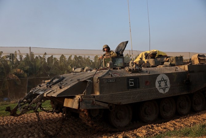 イスラエルとパレスチナ人イスラム組織ハマスとの戦闘中、装甲人員輸送車(APC)に乗るイスラエル軍兵士。2023年12月25日、イスラエル南部のガザとの境界付近(ロイター通信)