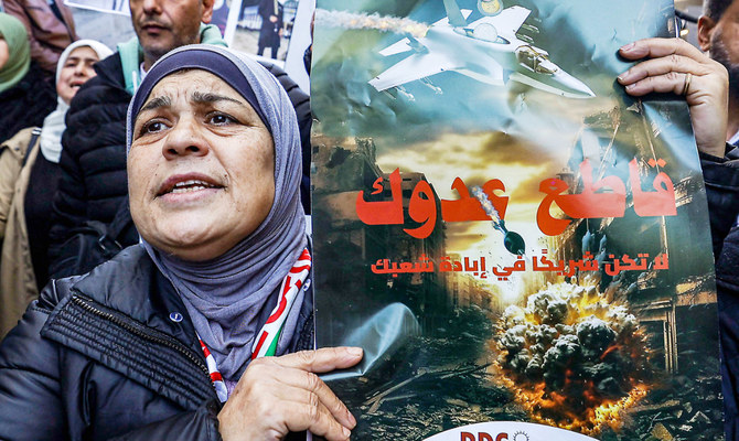 ラマッラーでイスラエル製品のボイコットを呼びかけるプラカードを掲げる女性。（AFP）