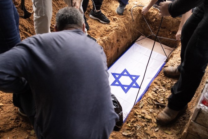 テルアビブ近郊のキブツ、シェファイムで行われた葬儀で墓に納められるアロン・シャムリズさんの遺体。シャムリズさんはガザでイスラエル軍に誤って殺害された。（AFP）