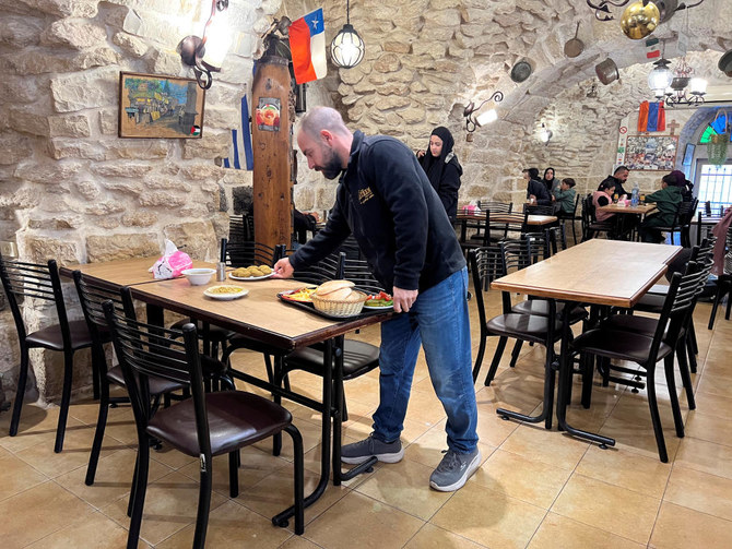 2023年12月9日、イスラエル占領下のヨルダン川西岸地区のベツレヘムにあるレストランAfteemで、店内のテーブルに料理を並べる4代目共同経営者Ala'a Salameh氏（42）。（Reuters）