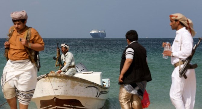 2023年12月5日、イエメンのAl-Salifの沖合に先月フーシ派に拿捕された商船「ギャラクシー・リーダー」が停泊し、武装した男性たちがビーチに立っている。（ロイター）