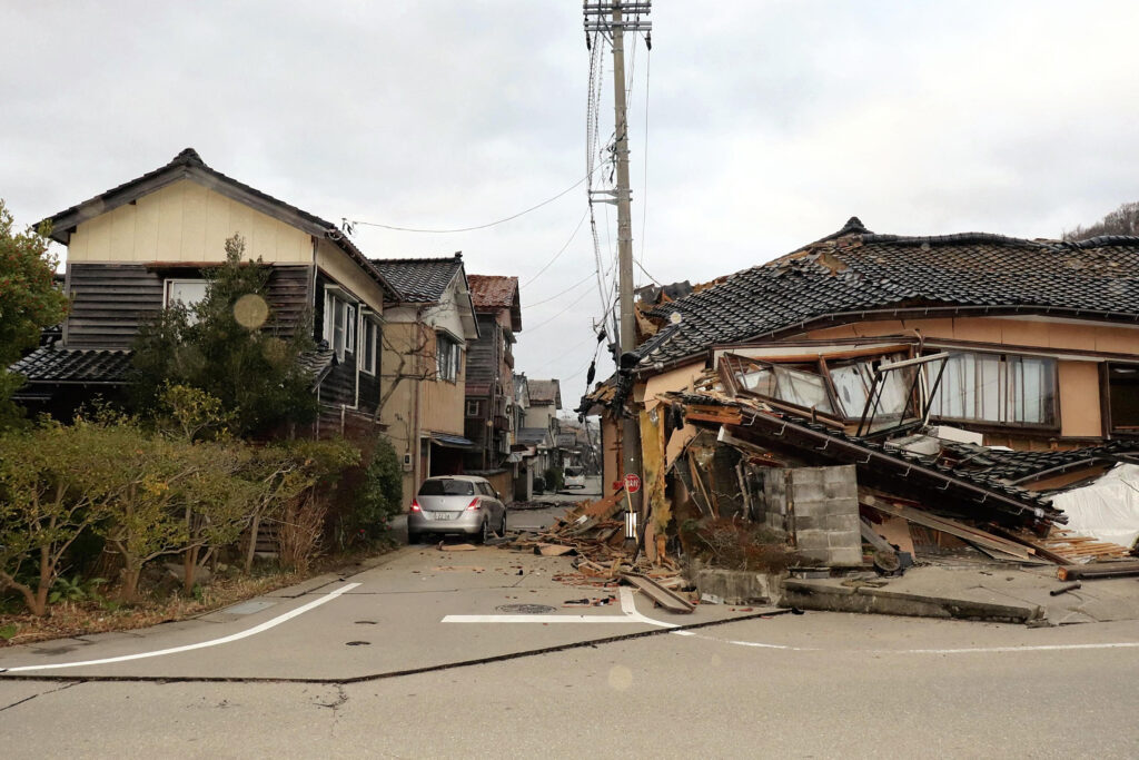 2024年1月1日午後、石川県能登地方を襲ったマグニチュード7.5の地震により、石川県輪島市の道路沿いで大きな被害を受けた建物の全景。(AFP＝時事）