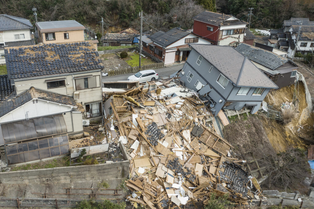石川県能登地方を襲ったマグニチュード7.5の大地震から一夜明けた2024年1月2日、石川県輪島市の道路沿いで損壊した家屋の空撮写真。(AFP＝時事）