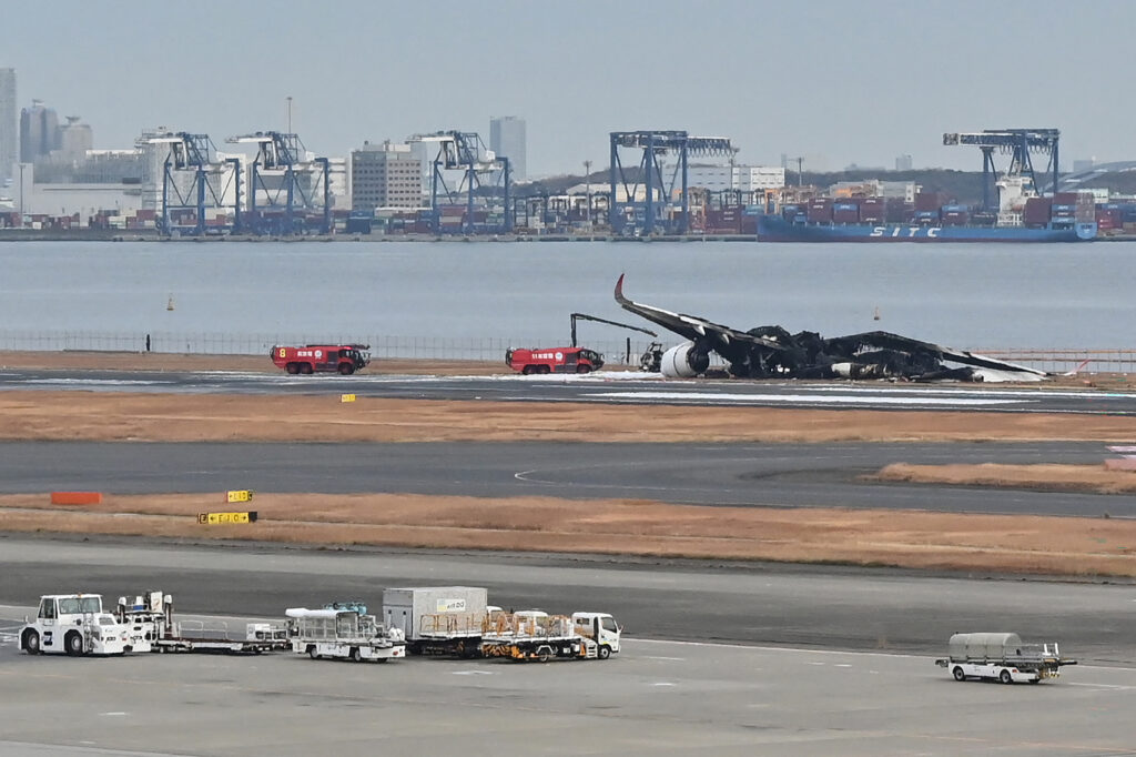 水曜日、滑走路に残された焼け焦げた旅客機の残骸が、乗客・乗員の命がいかに危なかったかを物語っている。(AFP=時事)