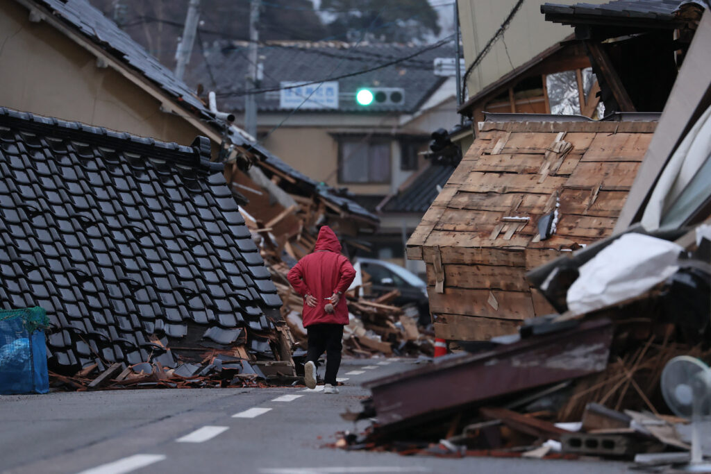 元旦に石川県能登地方を襲ったマグニチュード7.5の大地震から2週間後の2024年1月15日撮影。石川県輪島市で、倒壊した家屋が道路をふさいでいる。（AFP）