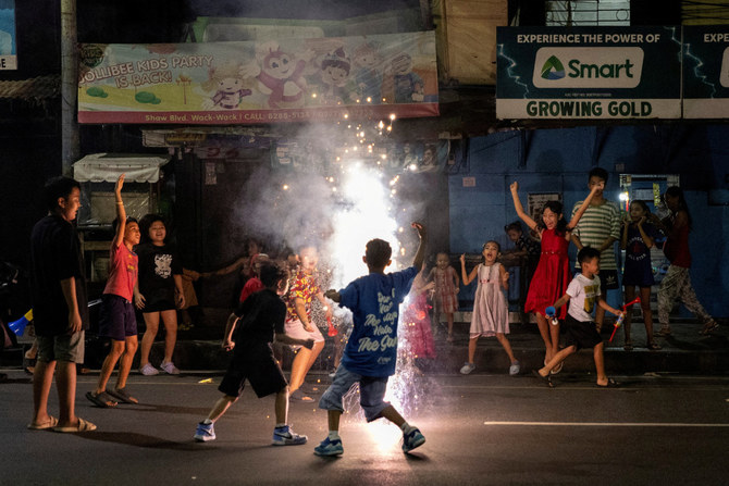 2023年12月31日、フィリピンのマニラ郊外マンダルヨンの通りで、大晦日のお祝いで遊ぶ子供たち。(ロイター)