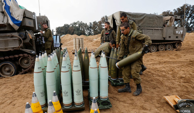 イスラエルとパレスチナのイスラム主義組織ハマスの対立が続く中、移動砲部隊の近くで砲弾を準備するイスラエル軍兵士。2024年1月2日、イスラエル。（ロイター）