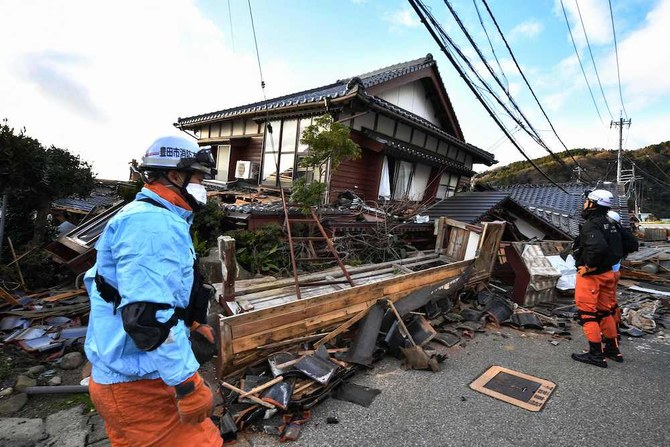 2024年1月2日、マグニチュード7.5の大地震の翌日、石川県輪島市で倒壊した木造家屋を点検する消防隊員。(AFP＝時事）