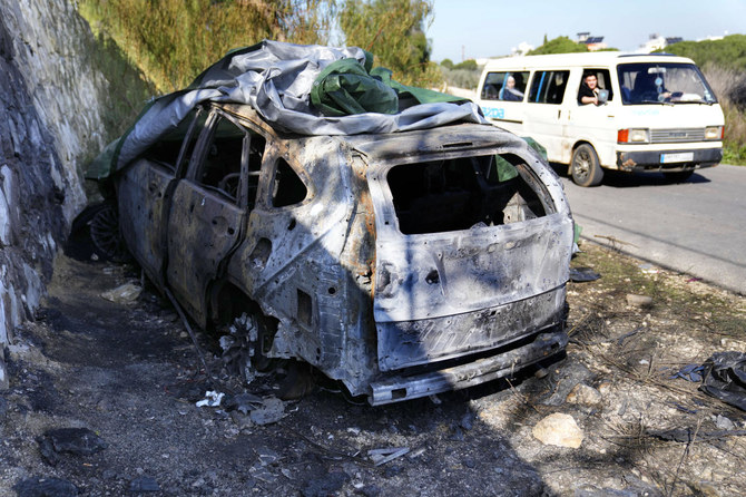 ヒズボラ司令官ウィサム・タウィル氏が使用していた車両の残骸のそばを通過するミニバン。司令官は8日、レバノン南部の村ケルベット・サレムで殺害された。2024年1月9日。（AP）