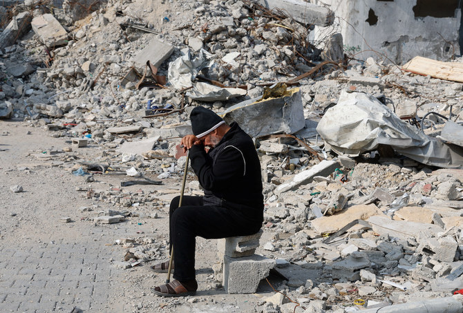 2024年1月9日、イスラエルとハマスの対立が続く中、イスラエル軍の攻撃で破壊された家屋の瓦礫の近くに座るパレスチナ人男性。(ロイター）