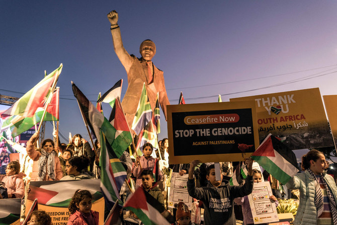 2024年1月10日、占領地ヨルダン川西岸地区のラマッラー。南アフリカがイスラエルを相手取って国際司法裁判所に提訴した画期的な「ジェノサイド」訴訟を祝福するため、故ネルソン・マンデラ南アフリカ大統領の銅像の周りに集まるパレスチナ人たち。（AFP）