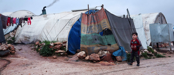 イドリブ県マアラット・ミスリンの町近くにあるシリア人難民キャンプのテントの前を歩く少年。（AFP）