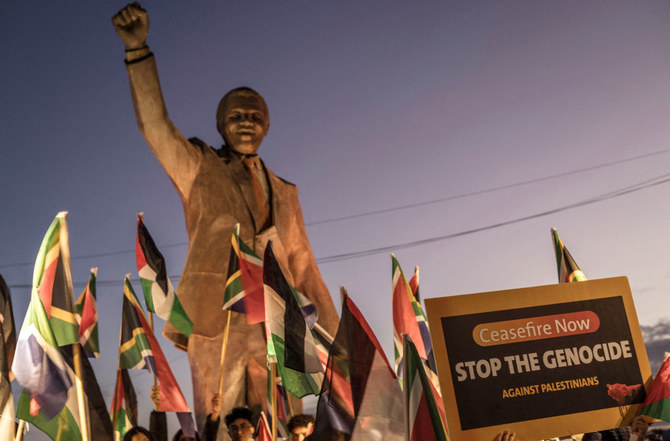 ヨルダン川西岸地区の占領地ラマッラーで、南アフリカがイスラエルを相手取って国際司法裁判所に提訴した画期的な「ジェノサイド」裁判を祝うため、故ネルソン・マンデラ大統領の銅像の周りに集まるデモ参加者たち。（AFP）
