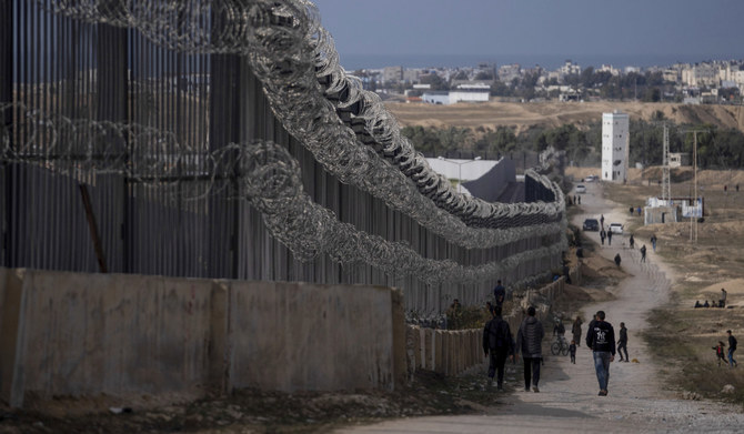 2024年1月14日、ガザ地区南部のラファ。イスラエル軍のガザ爆撃で避難民となったパレスチナ人らが、エジプト国境のすぐそばを歩く様子。（AP通信）
