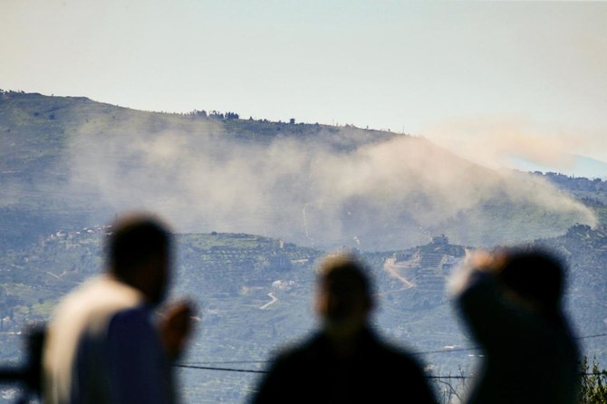 イスラエルとの国境に位置するレバノン南部のアダイセ村近くで、丘の向こうに上がる煙を眺める人々。ガザではイスラエルとパレスチナ武装組織ハマスの間で戦闘が続いている。（AFP）