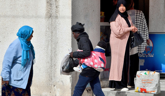 2023年2月24日、チュニスの郊外、バール・ラズレグで赤ちゃんを背中に背負って歩く女性（AFP）